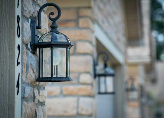 A black lantern is mounted on a stone wall.
