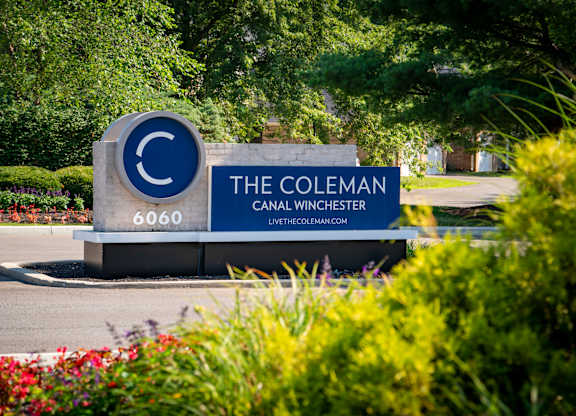 A sign for The Coleman Careal Winchester is displayed in front of some bushes.
