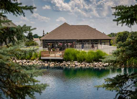 A building with a brown roof is surrounded by water and trees.