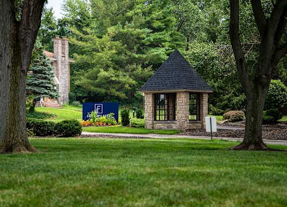 A small building with a black roof is surrounded by trees.
