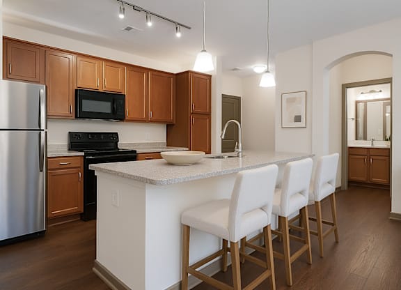 A kitchen with a white island and white chairs.