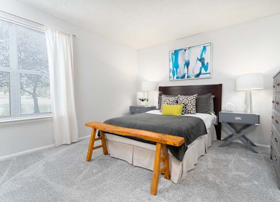 Bedroom with cozy furnishings and a large window letting in natural light