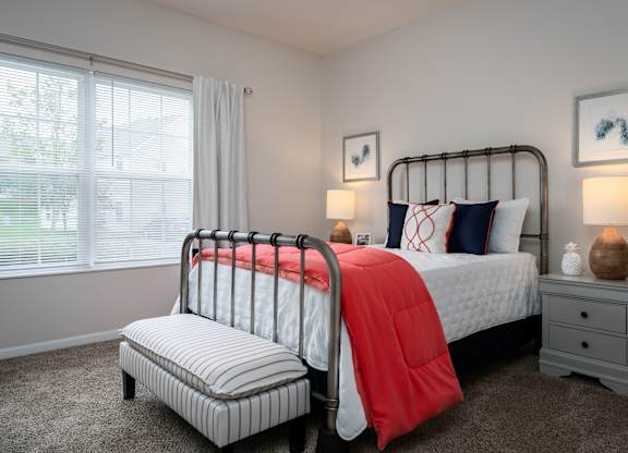 A bedroom with a large bed and a smaller bed with a red blanket.
