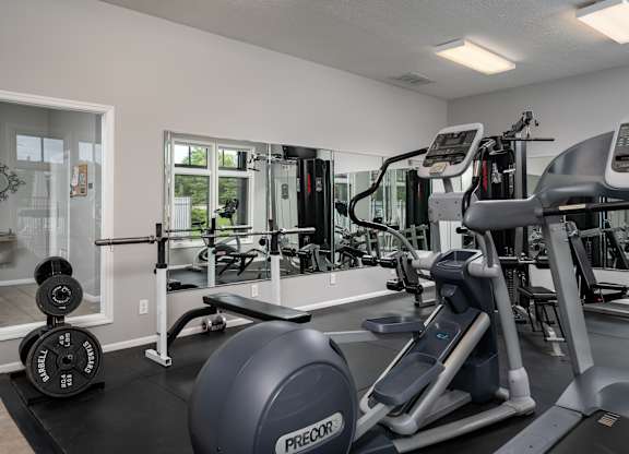A gym with a variety of equipment including treadmills, weights, and exercise machines.