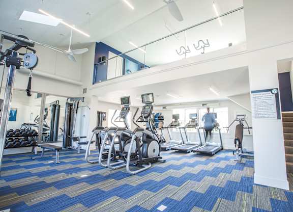 A gym with a variety of equipment including treadmills, weights, and exercise machines.