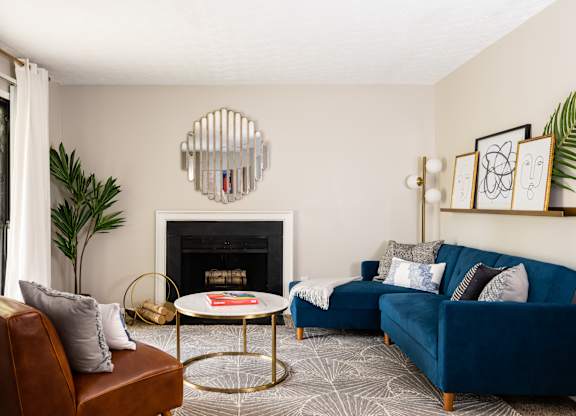 A living room with a fireplace, a blue couch, and a plant.