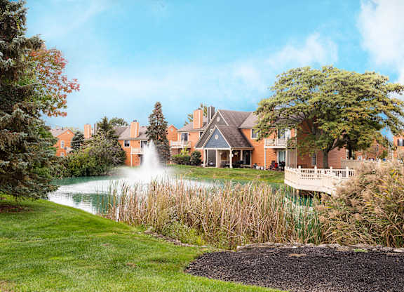 A fountain pond surrounded by trees and landscaped grounds.