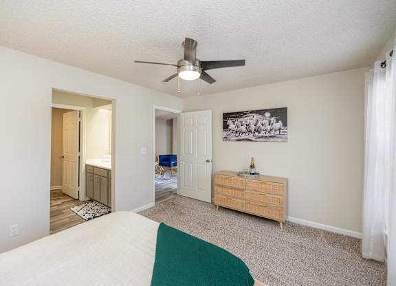 A furnished bedroom with carpeted flooring and a bathroom.