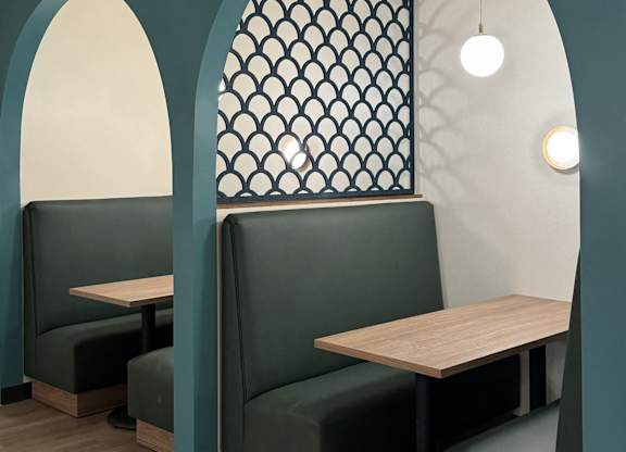 A restaurant setting with two tables and four chairs, framed by an elegant arched doorway.
