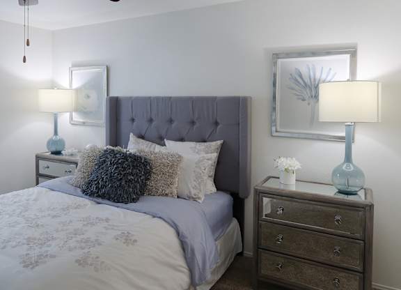 Stylish bedroom with plush carpet, ceiling fan, and vaulted ceiling in a one-bedroom apartment at The Boulevard