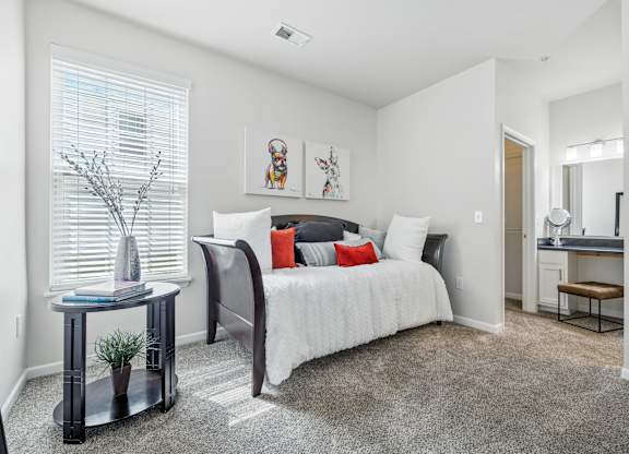 A bedroom with a bed, nightstand, and a window with blinds.