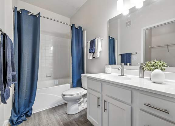 A white bathroom with a blue shower curtain.