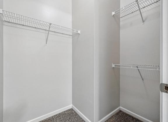 A white closet with two shelves and a carpeted floor.