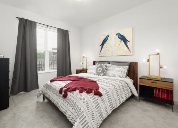 A furnished bedroom at Madamore with carpeted flooring and a window for natural light.
