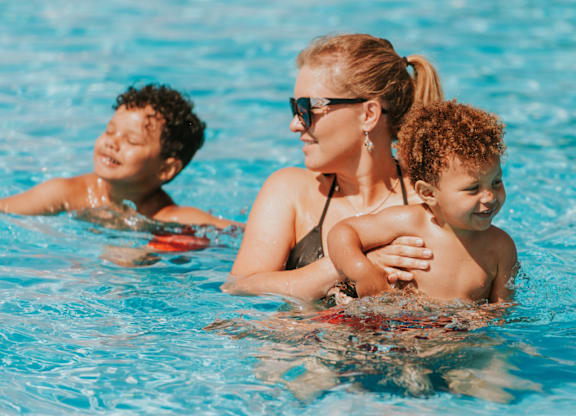 A woman and two children are swimming in a pool.