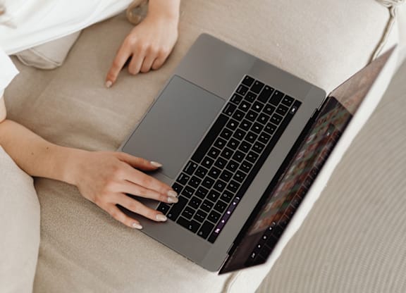 A person is typing on a laptop with a beige background.