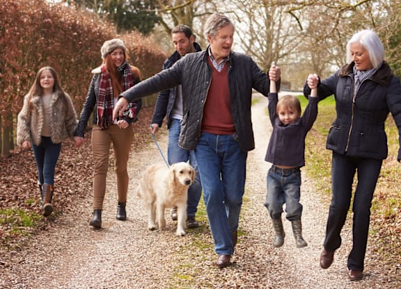 A family of five walking a dog on a path.