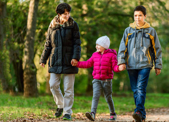 A family of three is walking in the woods.