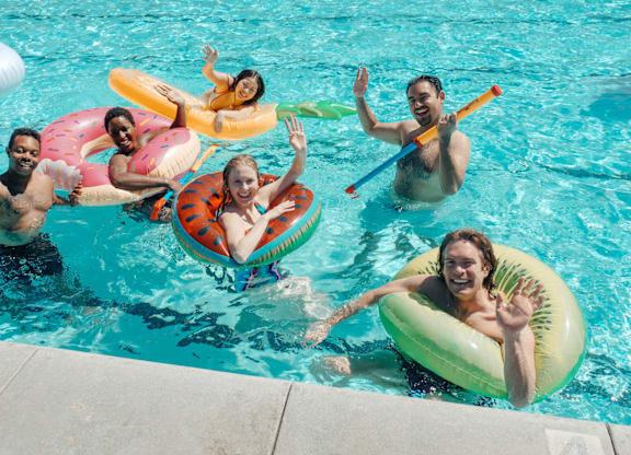 People in a pool with inflatable rings and floats.
