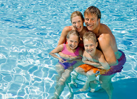 A family of four are enjoying a swim in a pool.