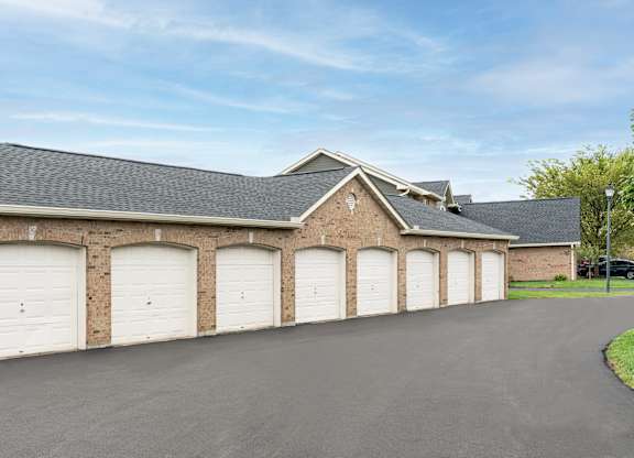 Brick building exterior featuring three garage doors and driveway access at The Coleman