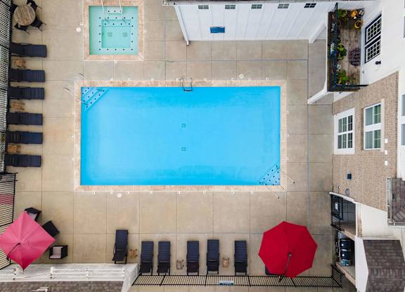 A large swimming pool surrounded by lounge chairs and umbrellas.