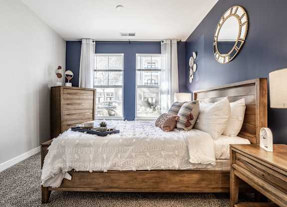 A bedroom with a large bed, a nightstand, and a window with curtains.
