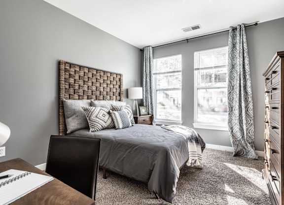 A bedroom with a bed, desk, and chair.