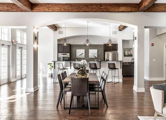 A dining room with a table set for six with a view of the kitchen.