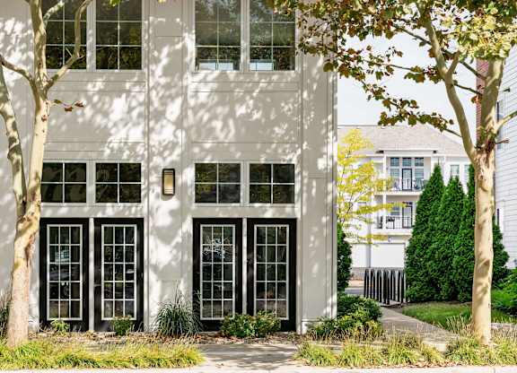 A white building with black windows and trees in front.