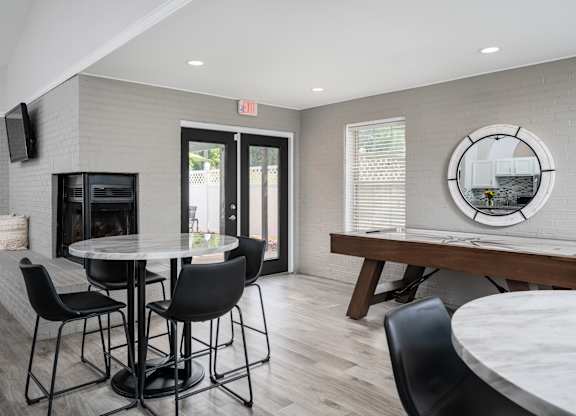 A clubhouse with a table surrounded by four chairs, and a door leading to outside.