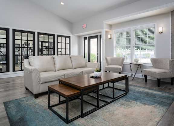 Community clubhouse at The Oaks with a couch and two chairs, next to a fitness center.