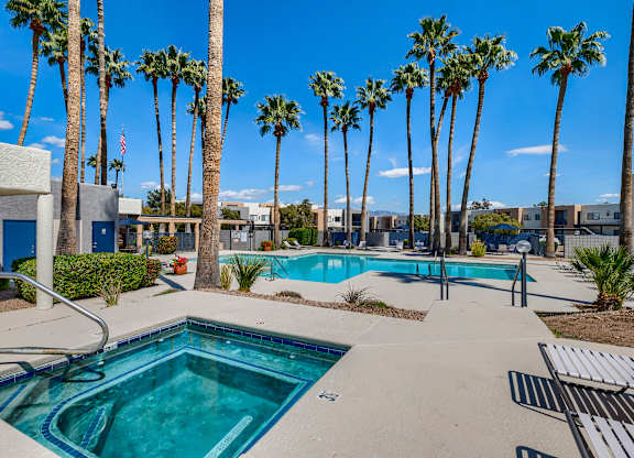 a swimming pool with palm trees in front of a building with a pool and chairs