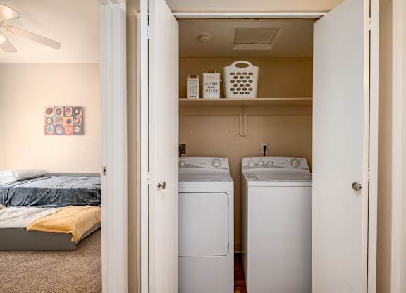 a bedroom with a washer and dryer and a closet with a bed