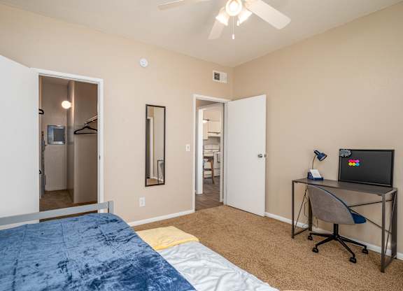 a bedroom with a large bed and a desk with a tv