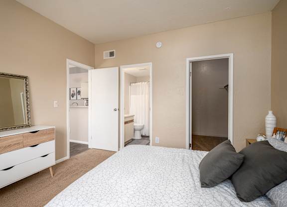 a bedroom with a large bed and a mirror and a bathroom