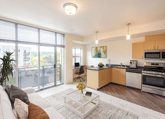 a living room with a couch and a coffee table and a kitchen with a sink