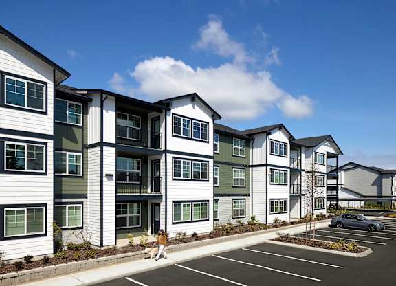 a rendering of a large apartment complex with a car parked in a parking lot