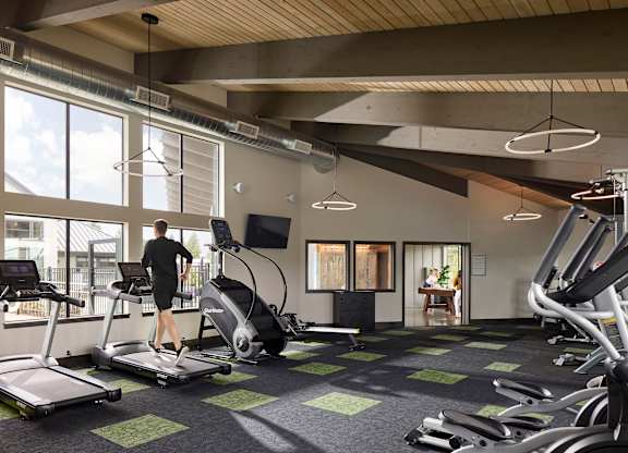 a man is running on a treadmill in a gym with large windows