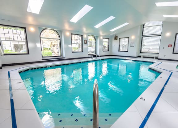 A large indoor swimming pool with a blue border and white tiles on the floor.