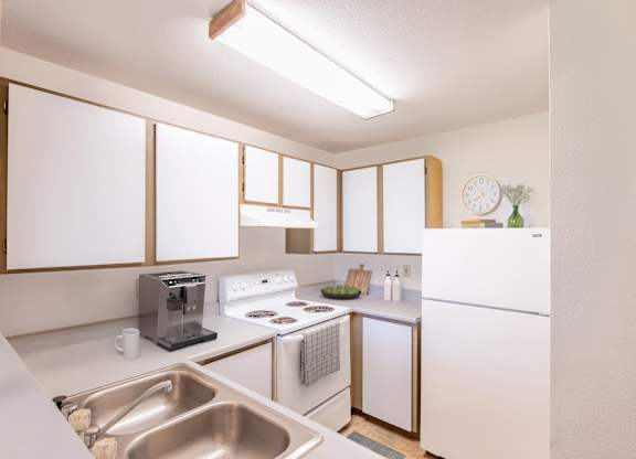 A kitchen with white appliances and a stainless steel sink.