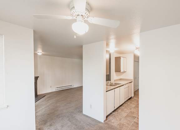 a kitchen and living room with a ceiling fan