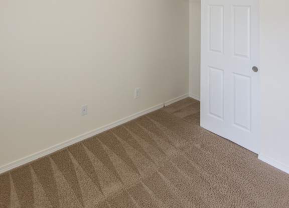 an empty bedroom with a closet and a white door