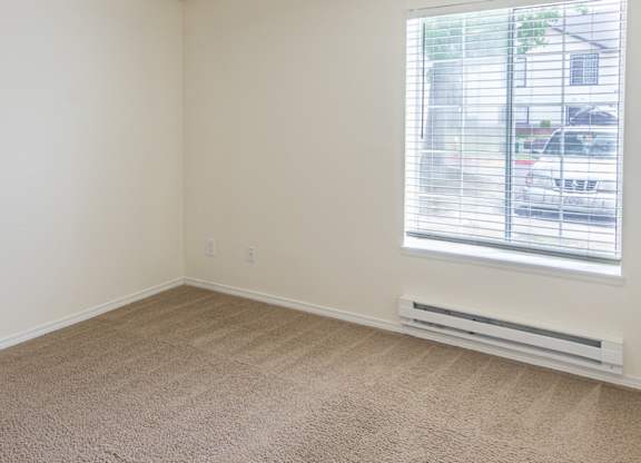 a bedroom with a large window and beige carpet