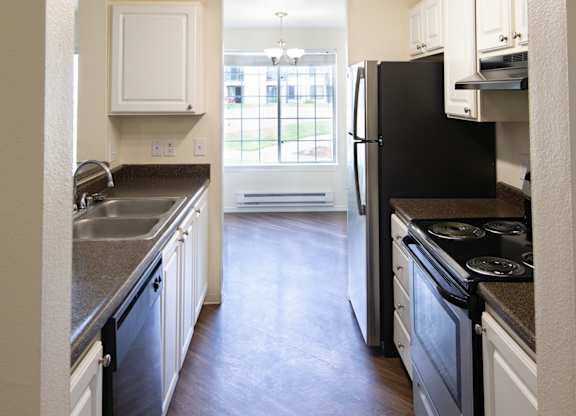 an open kitchen with white cabinets and black appliances
