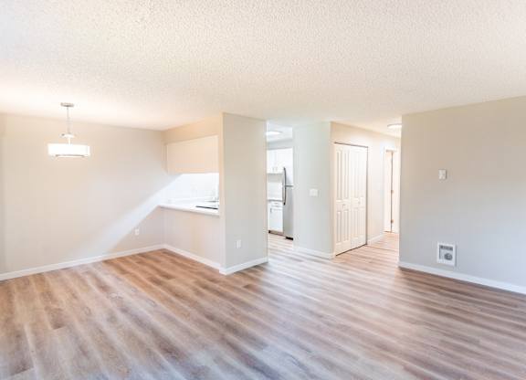 an empty living room and kitchen with a wood floor