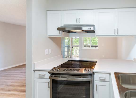an empty kitchen with white cabinets and a stainless steel stove
