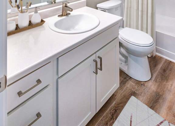 A bathroom with a white toilet, sink, and cabinets.