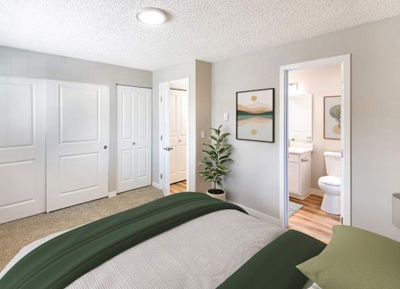 A bedroom with a bed in the foreground and a bathroom visible through the open door.