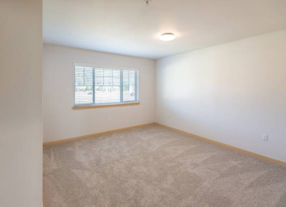 a bedroom with white walls and a window